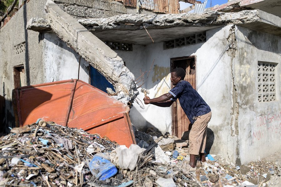 Ein Mann zerkleinert ein Dach auf Haiti